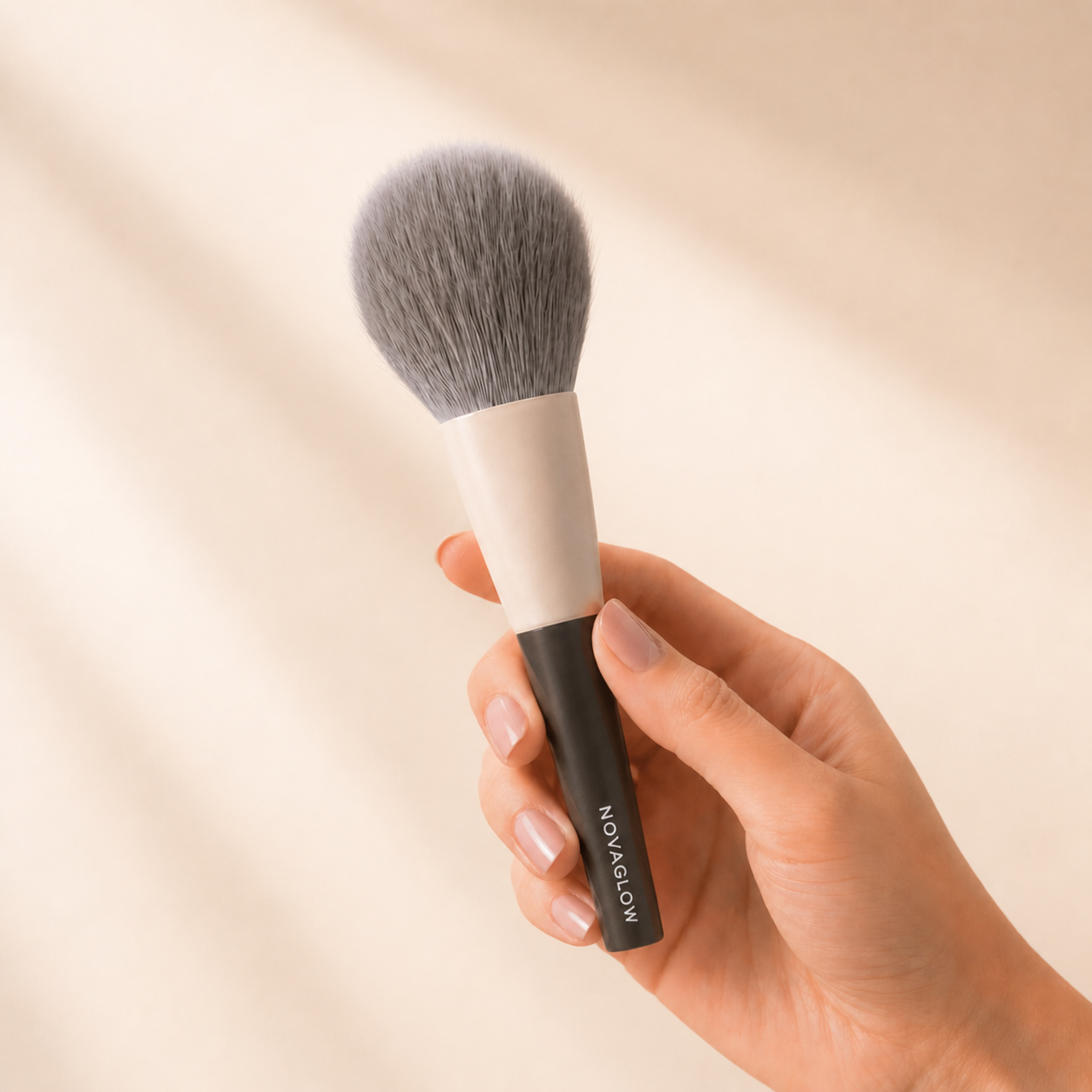 NOVAGLOW powder brush held in hand showing balanced weight and comfortable grip